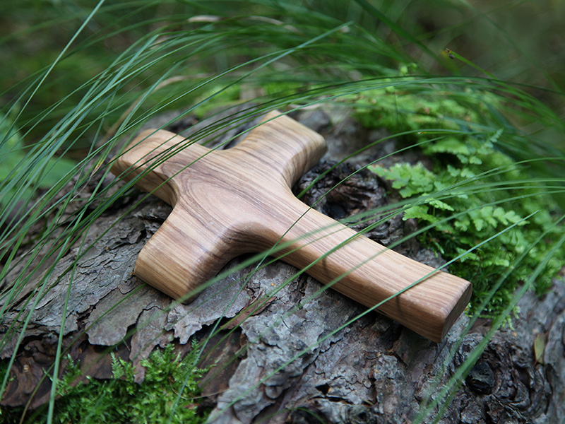 Ein Holzkreuz liegt auf einem Baumstamm